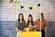 Hailey, Ciara, and Sarah smile behind a lemonade stand.